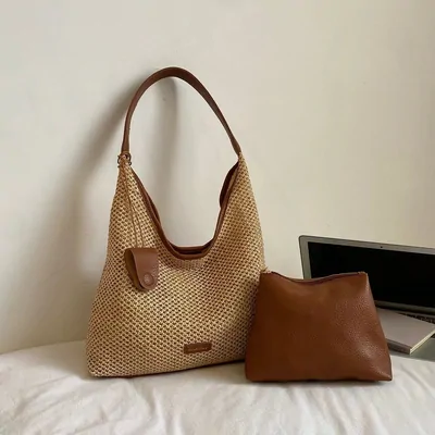 Bolso de rafia con asa de piel marrón y un neceser de piel junto a un portátil