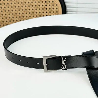 Cinturón de piel negra con hebilla metálica rectangular sobre una mesa blanca