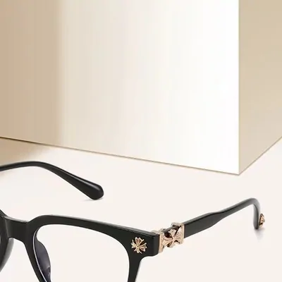 Gafas negras con adorno metálico en la varilla, sobre una superficie clara