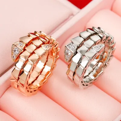 Dos anillos en espiral, uno en tono oro rosa y otro plateado, sobre un expositor rosa